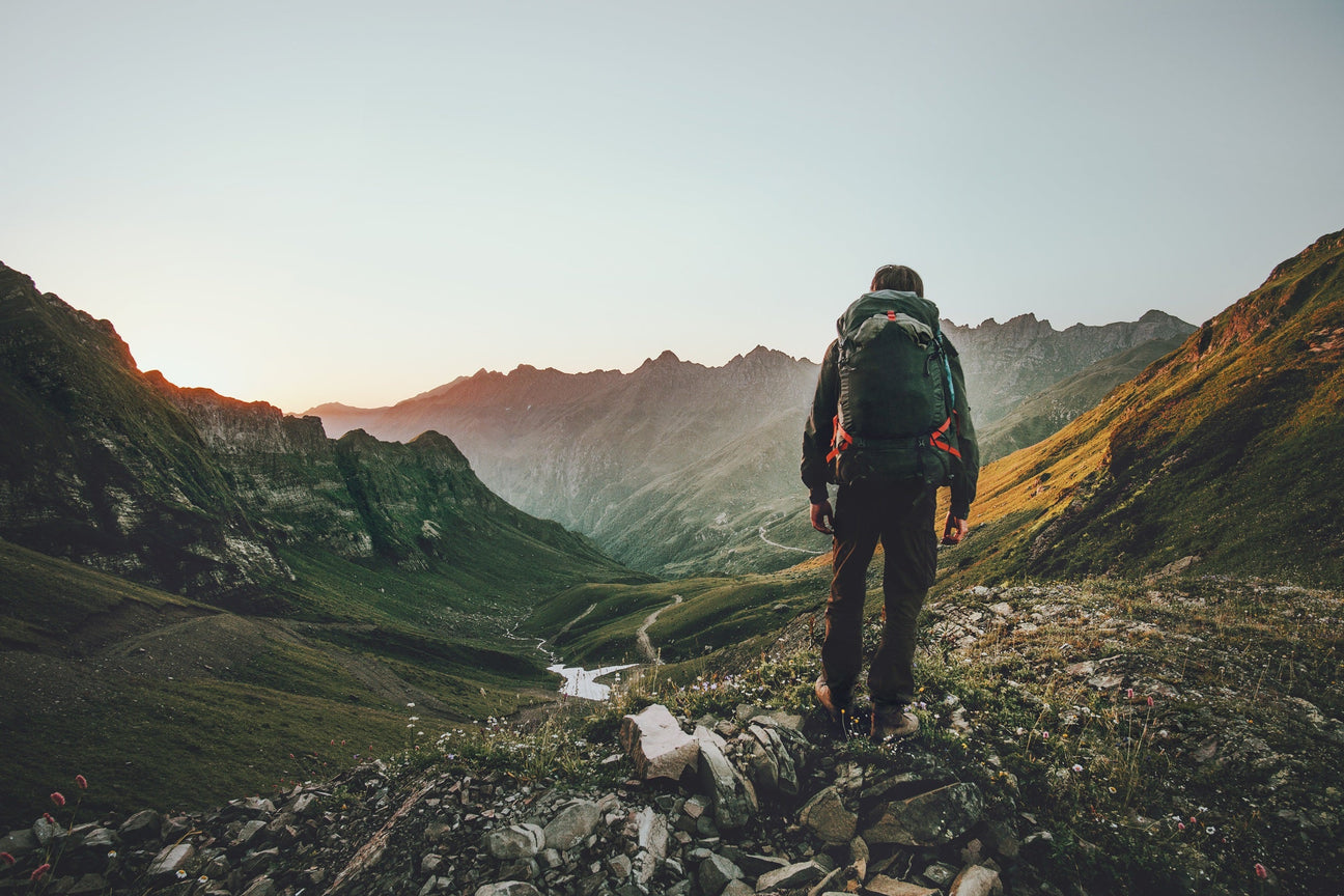 Abenteuerliche Berglandschaft mit Rucksackreisendem auf Felsgrat – Symbolbild für Bücher Reisen Abenteuer und Outdoor-Abenteuer Bücher